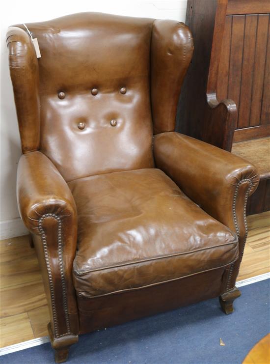 A pair of brown leather upholstered wing armchairs